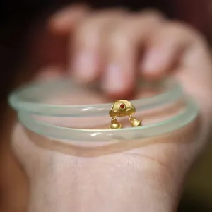 Gros plan sur un bracelet en calcédoine vert pomme avec un pendentif Ruyi en or et grelots