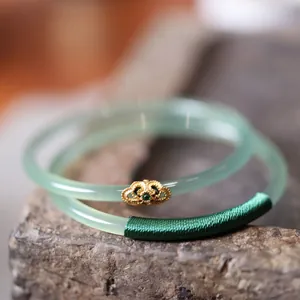 Close-up of green chalcedony bangles with gold ruyi metal inlay and green silk wrapping