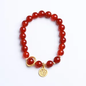 Natural 8mm red agate bead bracelet with golden Fu pendant charm on a white background