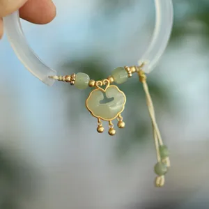 Detail of white chalcedony bangle with a golden Ruyi lock pendant and jade beads