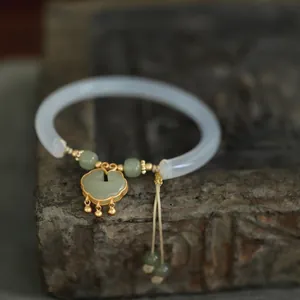 Natural chalcedony jade bangle with golden Ruyi lock charm and tassel accessory