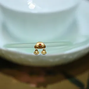 Vue macro detaillee d'un pendentif verrou ruyi dore avec pierre rouge et cloches sur jade
