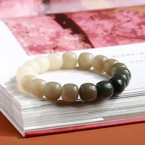 Natuurlijke bodhi-zaden armband met groen verloop op een vintage boekwerk