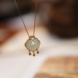 Macro shot of Ruyi lock pendant in gold with natural white chalcedony and small beads