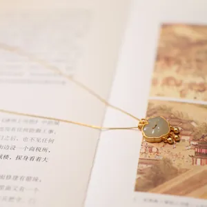 Detailed close-up of a gold Ruyi lock pendant necklace with natural white chalcedony stone
