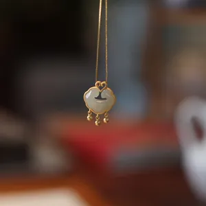 Detail view of Ruyi lock pendant with green jade, heart buckle and gold metal finish