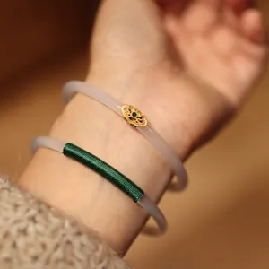 Detail of chalcedony bangles with gold filigree, green zircon and silk wrap on wrist