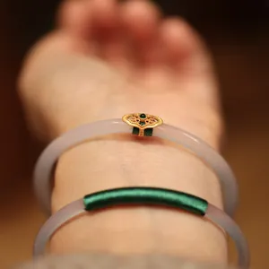 Detailed close-up of lavender chalcedony bangles with green gemstone and gold silk wrap