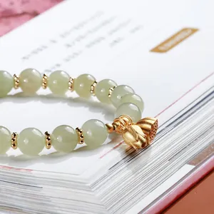 Natural green jade bead bracelet featuring elegant gold lotus and seed pod pendants