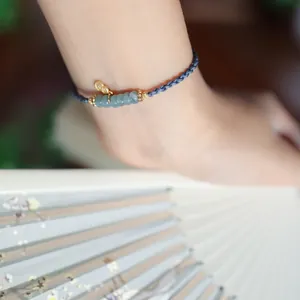Detail eines handgewebten Armbands mit Jadeperlen und goldenem Kürbis-Anhänger am Handgelenk