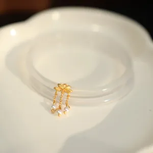 Eleganter Goldlotus-Anhänger mit Perlenquasten an einem durchscheinenden Armreif