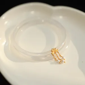 Chalcedon-Achat-Armreif mit goldenem Lotusanhänger und weißen Perlen auf Keramikschale