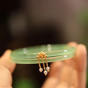 Nahaufnahme grüner Achat-Armreifen mit goldenem Lotus-Anhänger und feinen Perlen