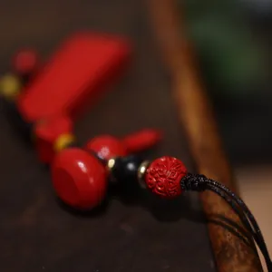 Detail van rode cinnaber kalebas hanger met gesneden kralen en gouden accenten
