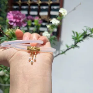 Details von Chalcedon-Armreifen mit goldenen Blumenanhängern und Perlenquasten