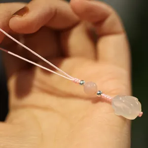 Detail of hand-woven pink chalcedony rabbit pendant with translucent beads and metallic accents