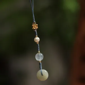 Macro detail of handmade beaded charm with green jade donut and blue braided cord