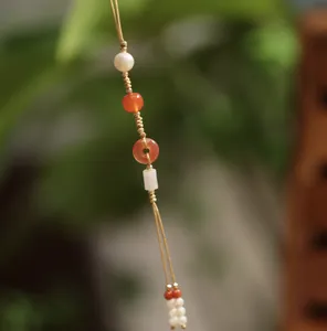 Detail of natural agate beads and jade pendant on a handcrafted braided phone charm