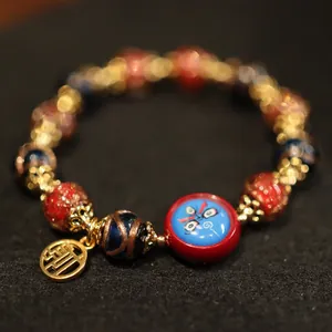 Detail of beaded bracelet with red enamel bead featuring a Beijing Opera facial mask