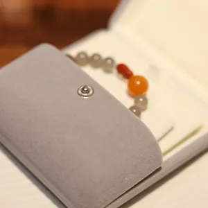 Agate bead bracelet with orange stone on a grey velvet pouch with metal snap button