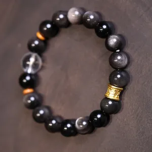 Detalle de cuentas de obsidiana plateada con cristal transparente y separador dorado grabado