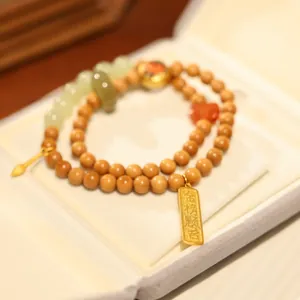 Detail of wooden beaded bracelet with green jade and Jinbangtiming gold pendant in a box