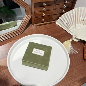 Elegant square dark green velvet jewelry box with gold label on white display tray