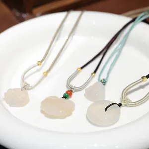 Detailed display of assorted white jade pendants including Buddha and flower designs