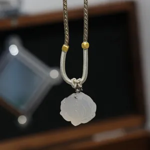 Detailed macro view of white chalcedony lotus pendant with golden woven necklace cord