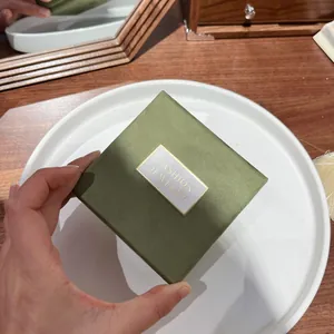Close-up of a matcha green square jewelry gift box with soft texture and gold accents