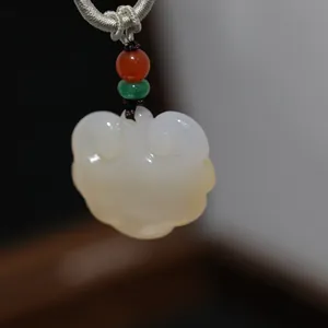 Macro detail of white chalcedony Ruyi pendant with red and green bead accents