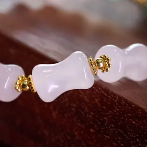 Macro shot of bamboo-style pink quartz beads and textured gold spacer beads on a bracelet