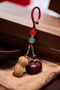 Détail macro du porte-clés cacahuète et persimmon en bois avec breloque de fortune