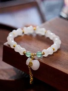 Close-up of bamboo-style jade bracelet with gourd pendant and golden silk tassel