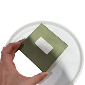 Textured matcha green square jewelry gift box with gold logo label held in hand