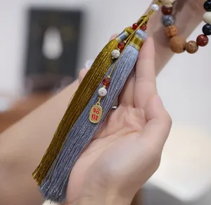 Detail of multi-gemstone prayer beads featuring dual-tone tassels and lucky charm