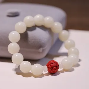 Macro shot of 12mm white jade bodhi beads with a red cinnabar pixiu carving on a velvet box