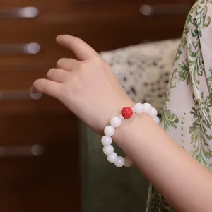 Detail of white Bodhi seed bracelet with red cinnabar bead worn on a female wrist