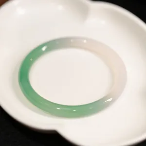 Eleganter 8mm grün-weißer Chalcedon-Jaspis-Armreif auf weißem Keramikteller