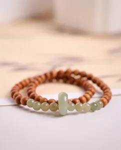 Detailed close-up of double-layer sandalwood and jade bead bracelet with Zen style