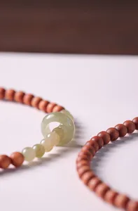Macro detail of red sandalwood beads and green jade ring on a double-layer bracelet