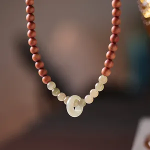Macro detail of sandalwood and jade beads with a round jade ring on a double-loop bracelet