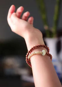 Close-up of sandalwood and jade bead bracelets stacked on a wrist with minimalist design