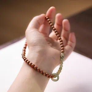 Detail of wooden beads and green jade pendant on a traditional Chinese style bracelet