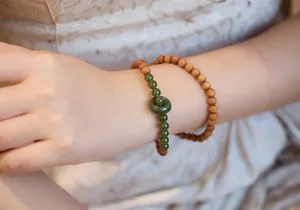 Detail of stacked sandalwood beads and green jade ring bracelet on a wrist