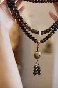 Detail of Zen style Buddhist prayer beads with deep green beads and carved lotus pendant