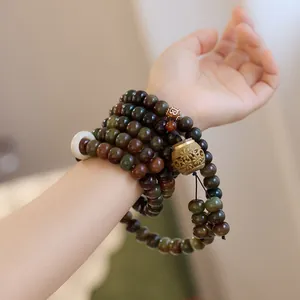 Detail of vintage multi-loop jade bodhi seed bracelet with carved golden pendant
