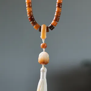 Close-up of weathered bodhi seed beads with a white silk tassel and lotus charm