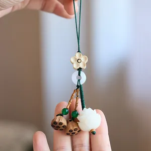 Close-up of a Zen-style lotus keychain with wooden lotus pods and white jade-like flower