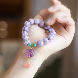 Macro detail of purple pumpkin beads and guardian lion pendant on a beaded bracelet